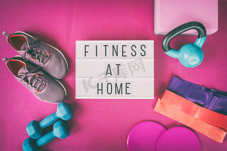 家庭健身标志，配有粉色瑜伽垫、跑鞋、壶铃重量和哑铃阻力带和滑块，用于普拉提在线课程。