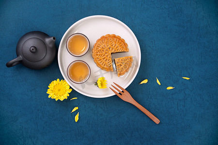 简约创意设计背景摄影照片_中秋节蓝色背景月饼的简约布局，创意食品设计理念，顶视图，平躺，复制空间。