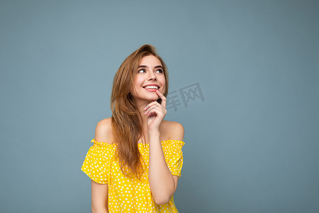 金发带摄影照片_年轻的微笑美丽的深色金发女人带着真诚的情感被隔离在背景墙上，复制空间穿着时尚的夏季黄色连衣裙。
