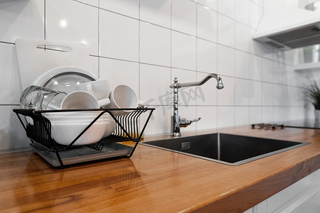 碗碟架可在木质台面、白色墙砖、水槽和水龙头上放置许多碗碟和杯子。