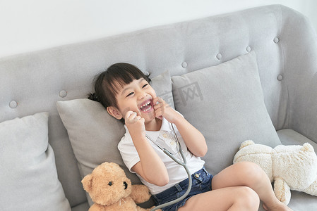 亚洲小女孩玩洋娃娃玩具。亚洲小女孩手里拿着听诊器检查洋娃娃玩具。
