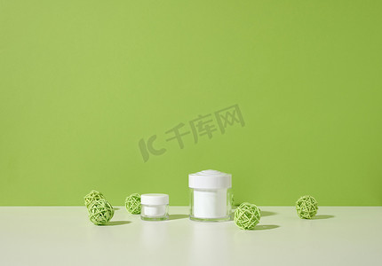 白色桌子上的化妆品用空白色罐子，绿色背景。