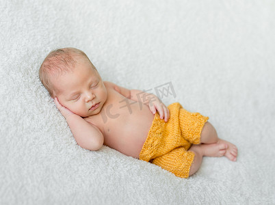梦幻甜蜜摄影照片_穿着黄色内裤的甜蜜熟睡的新生男孩