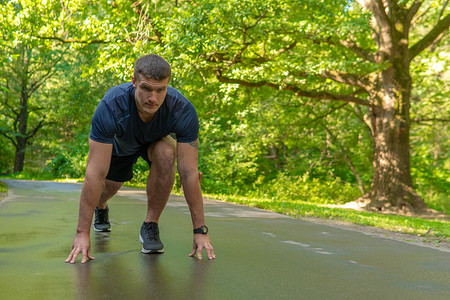 一名男子运动员在户外的公园里跑步，在森林周围，橡树绿草年轻持久的运动员跑步健身适合人运动，外面的树木。