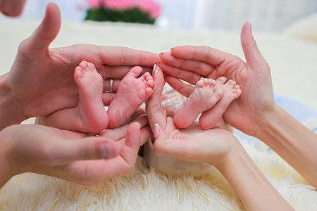 爸爸妈妈手握着两个刚出生的双胞胎婴儿的小腿