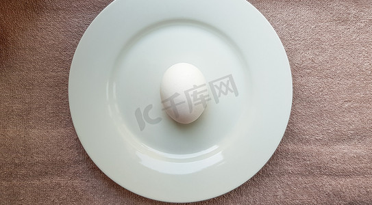 白盘子上的一个完整的生鸡蛋