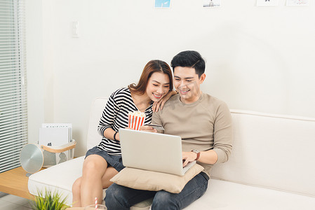 亚洲年轻夫妇使用笔记本电脑购买电影票在线支付
