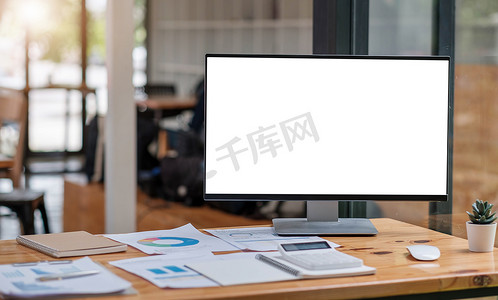 简单工作区的特写视图，带有开放式空白屏幕笔记本电脑、框架和笔记本电脑，放在白桌上，办公室背景模糊