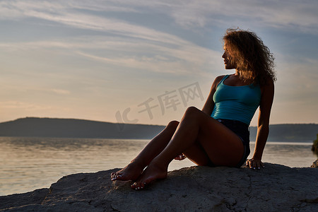 女孩坐在石头上欣赏风景。
