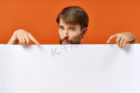 广告海报摄影照片_广告海报在一个橙色背景的男人手中，他用手示意 Copy Space 模型