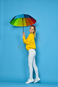 身穿黄色毛衣、带五彩伞的女人摆出彩虹色