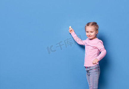 黑板蓝色背景摄影照片_蓝色背景中用粉笔的小女孩