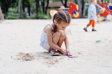 小女孩在操场上玩沙盒 挖沙铲 建筑沙图 夏日