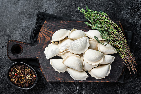 生饺子摄影照片_冷冻生饺子 pierogi 与土豆在木板上。