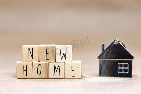 new设计摄影照片_New Home 文本以木制立方体背景书写，带有舒适小房子的象征，背景设计模糊，购买房地产，抵押贷款，业主概念背景