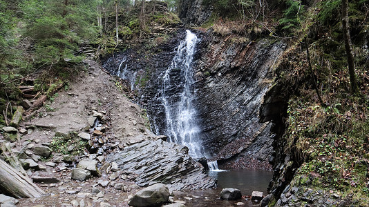 瀑布水流摄影照片_在一个有石墙的小峡谷中的瀑布。