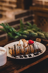 竹枝摄影照片_靠近竹枝的圣诞盘子上放着草莓的果馅奶酪卷的特写。