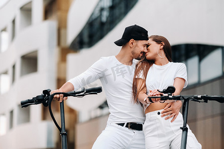 一对骑着电动滑板车的情侣在城市里拥抱，一对情侣骑着滑板车相爱