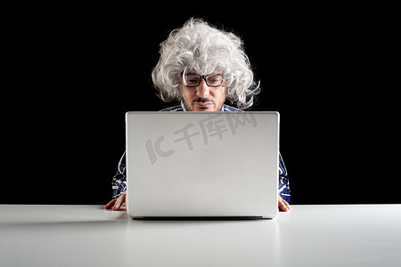 婴儿潮摄影照片_婴儿潮一代专注于老年人集中坐在办公桌前看着笔记本电脑
