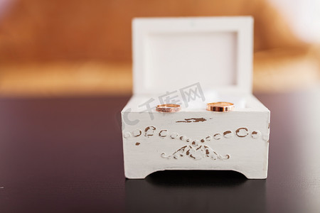 一对金色结婚戒指，白色破旧的装饰盒上镶有钻石。
