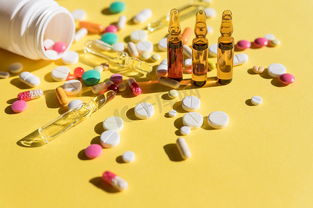 黄色背景中分离的医用安瓿、瓶子、药丸。选择性聚焦。注射用安瓿。医学背景。冠状病毒流行病。医药