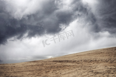 多云天空下干燥沙漠中的沙尘暴