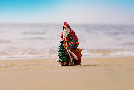 沙滩大海海报背景摄影照片_夏天在沙滩上的圣诞老人。