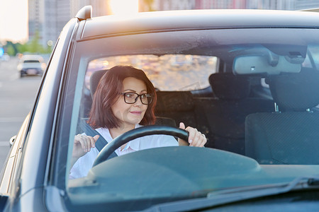 公路运输摄影照片_戴眼镜的中年女司机，女司机开车。