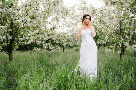 白色的裙子摄影照片_新娘穿着白色的裙子，拿着一大束春天的花束