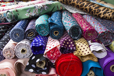 在商店货架上制作丝绸和布料，在市场上轧制丝绸，多色和多种图案纹理背景。