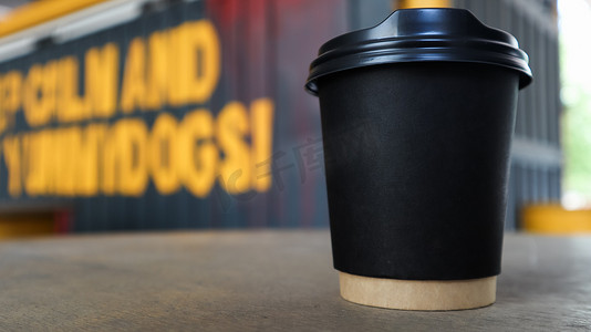 城市一家街头咖啡店的木桌上没有文字和标志的黑色纸杯，咖啡上有塑料盖。