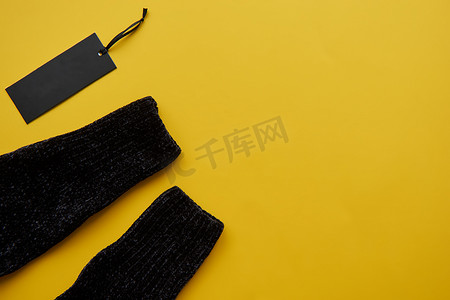 黑色舒适套头衫和纸标签隔离在黄色纸背景上。