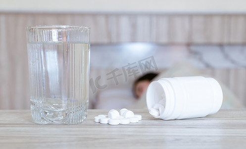 药摄影照片_感染感冒的流感药妇女将药物放在桌子上和一杯水上。