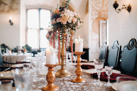 烛光晚餐摄影照片_城堡的桌子上有鲜花的婚礼餐桌装饰，烛光晚餐的餐桌装饰。蜡烛晚餐