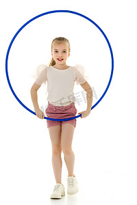 一个身穿白色 T 恤的小女孩用铁环做运动。