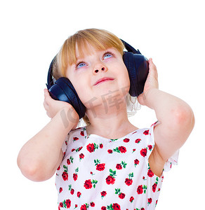 非常喜欢音乐的小女孩通过大的黑色耳机听音乐很开心。