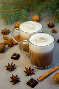 可可咖啡摄影照片_热圣诞饮料可可咖啡或巧克力加牛奶奶油在一个小透明杯子里。