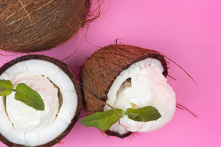 香草冰淇淋球摄影照片_粉红色背景中用薄荷叶装饰的新鲜椰子半香草冰淇淋球