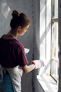 穿白围裙的女人在房屋室内装修中画窗户