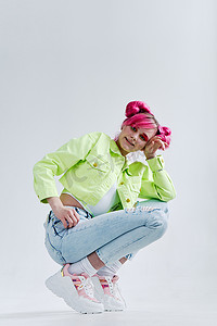 孟菲斯明黄背景摄影照片_漂亮的女人粉红色的头发摆着时尚的衣服孤立的背景