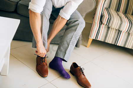 穿鞋子摄影照片_穿灰色长裤和紫色裙子袜子棕色鞋子的男人