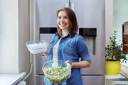 微笑的女人手里拿着一碗冰和一盘蔬菜沙拉