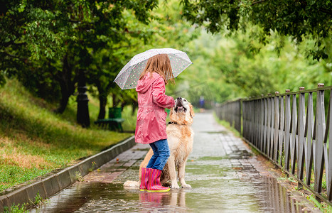 有狗的小女孩在雨下