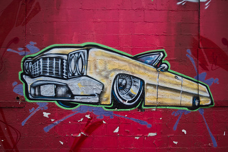 车辆绘摄影照片_亮红砖墙上绘有一辆黄色古董敞篷车的壁画