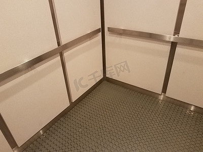 电梯内部有灰色地板、金属条和白色墙壁