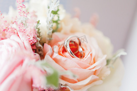 金色的花朵摄影照片_一对金色结婚戒指位于新娘花束的花朵内。