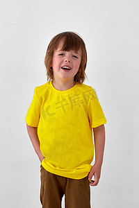 穿着休闲黄色服装的积极小男孩站在白色背景上