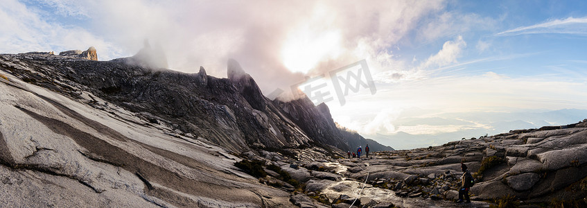 登山者在日出时沿着京那巴鲁山的岩石山坡跋涉