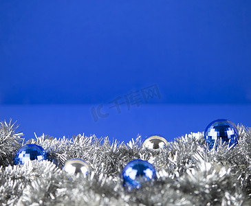 蓝色背景的银色装饰链花环中带有蓝色和银色亮色小饰物的圣诞复制空间，具有散景效果
