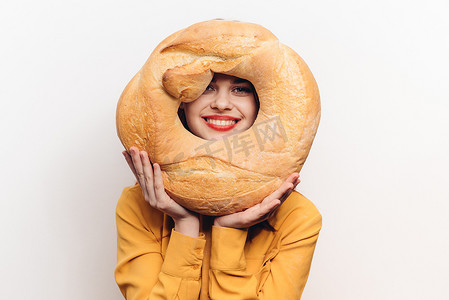 淡色国风水墨背景摄影照片_淡色背景下，妆容鲜艳的女人手里拿着一条圆面包 Copy Space
